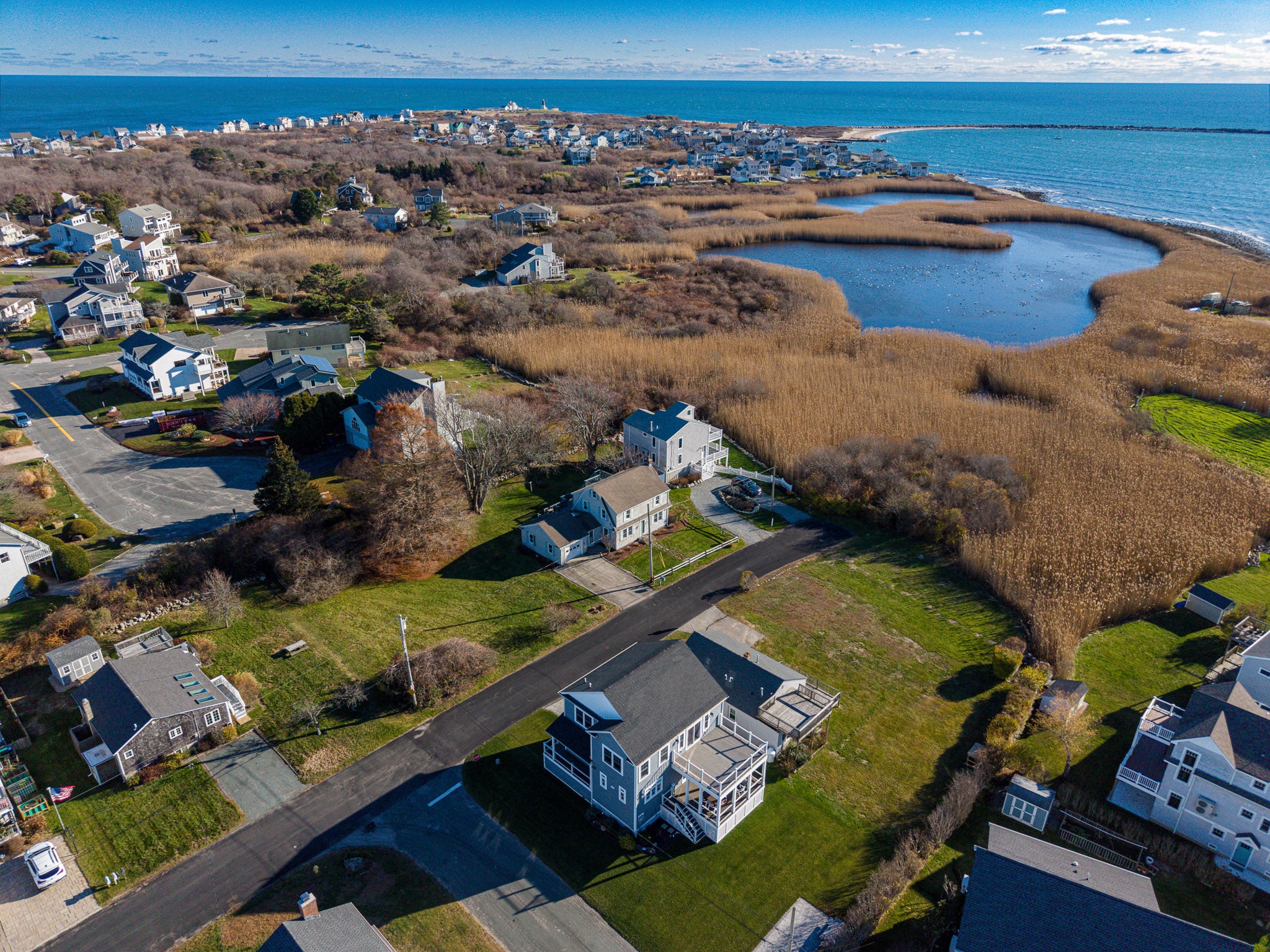 Aerial view of a coastal area with houses, roads, and a body of water.