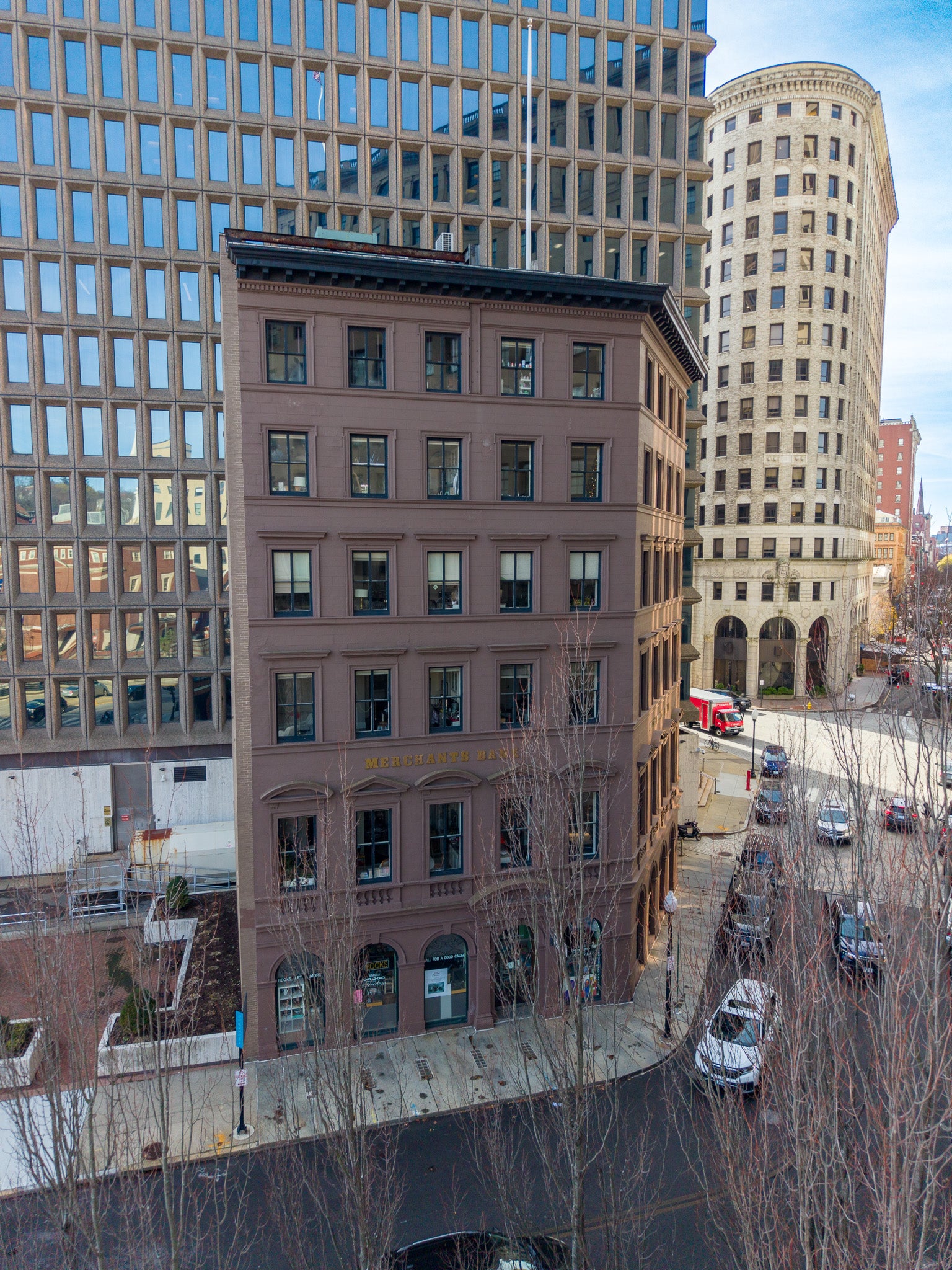 Tall brown building in an urban setting with other buildings and street in the background