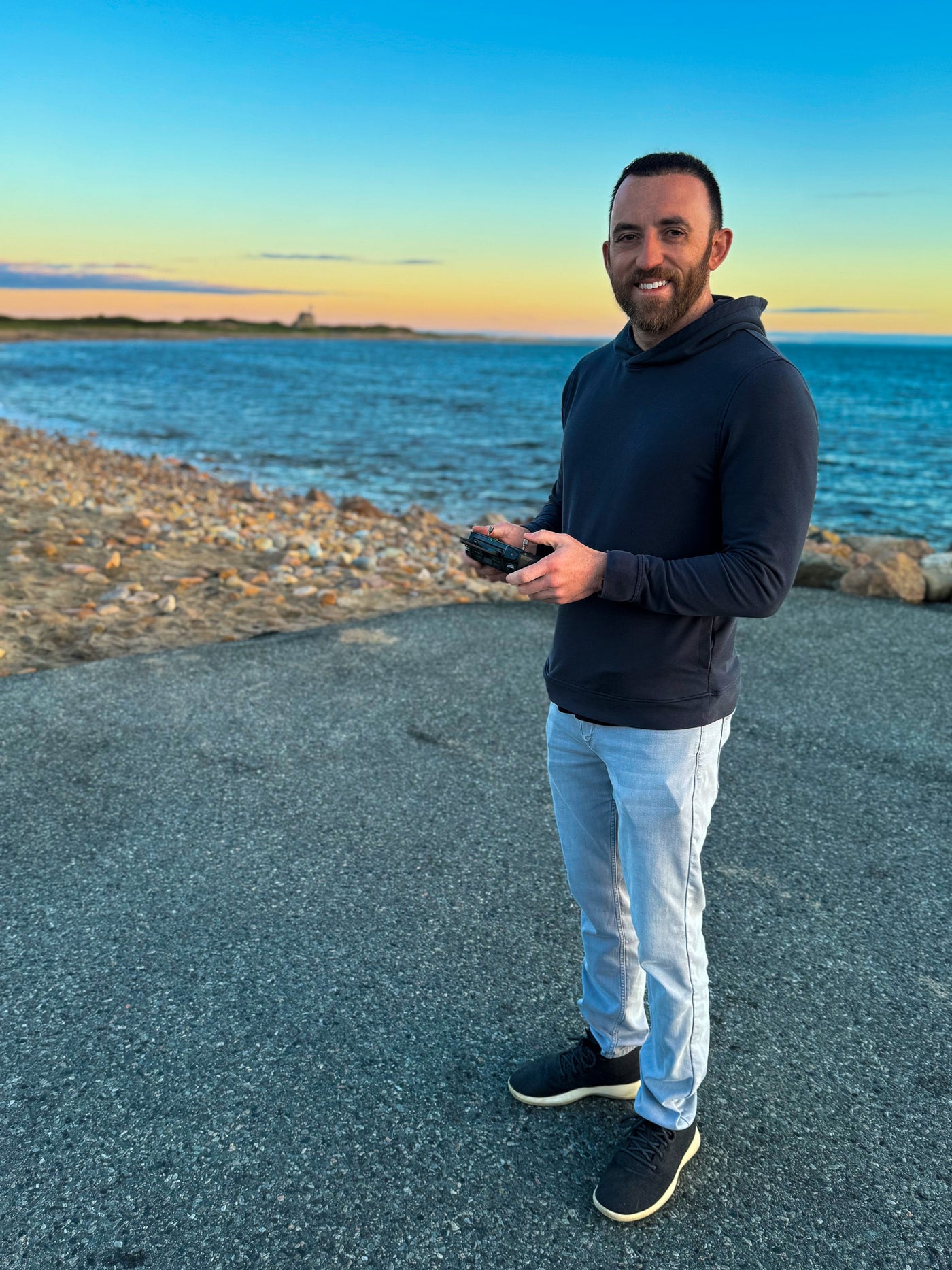 Man standing on a path by a body of water with a sunset in the background