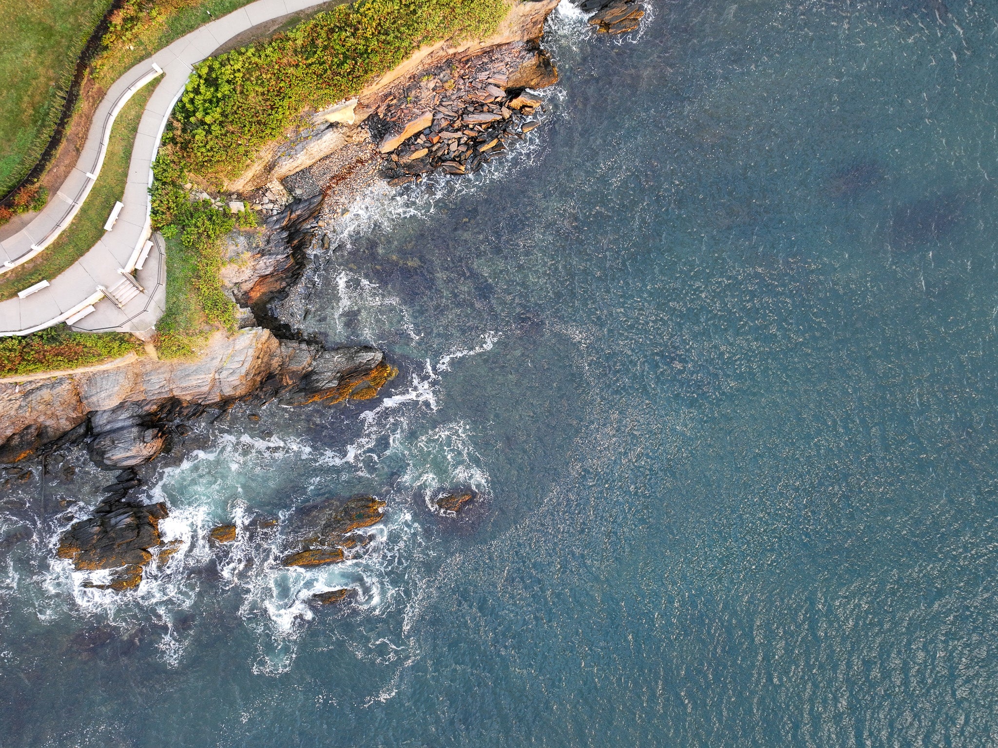 Aerial view of a rocky coastline with waves crashing against the shore.