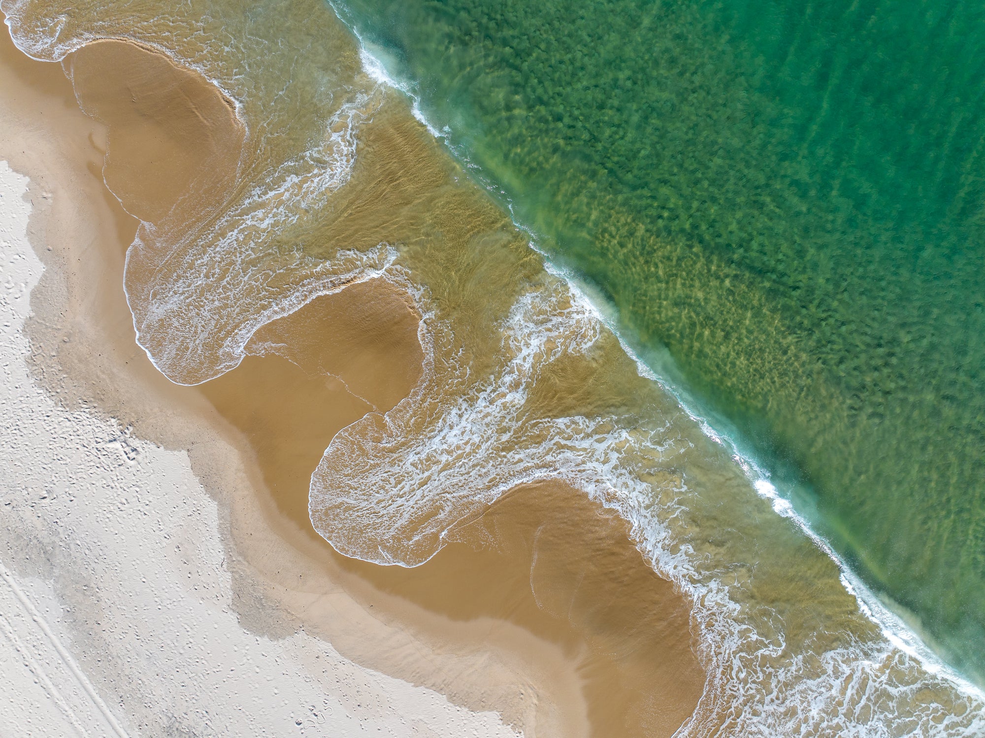 Aerial view of a beach with waves crashing onto the shore.