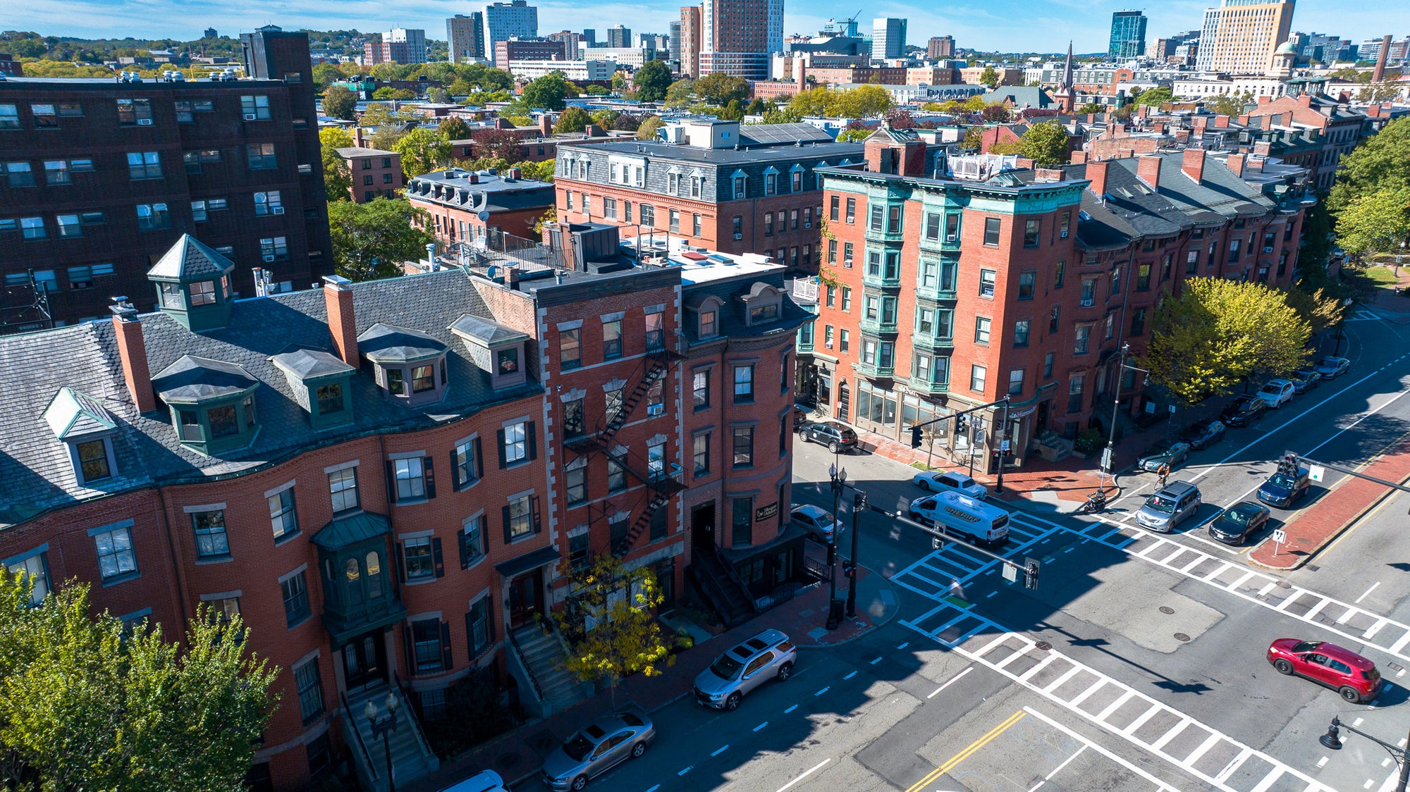 Aerial view of a city street with brick buildings and cars on a clear day.