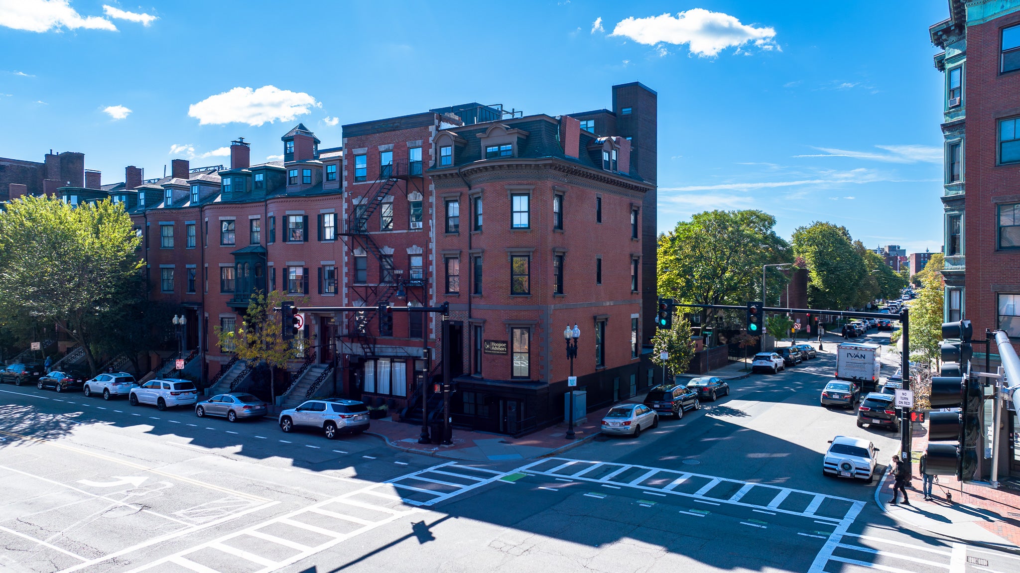 Street view of a city block with red brick buildings and cars on a clear day.